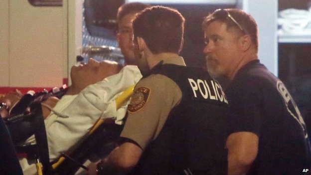 Paramedics carry on a stretcher one of the two injured police officers in Ferguson